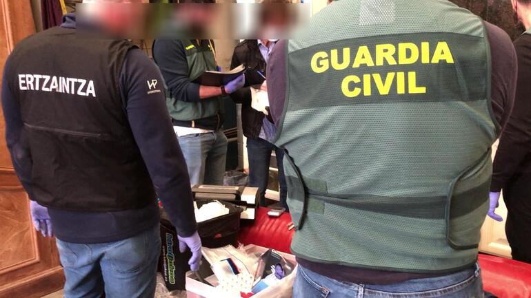 "Agentes de la Guardia Civil y de la Ertzaintza colaboran durante una operación conjunta, con ambos uniformes visibles."