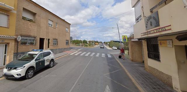 Patrulla de la Guardia Civil estacionada junto a un paso de peatones en una calle urbana de Riba-roja de Túria, con edificios residenciales a ambos lados.